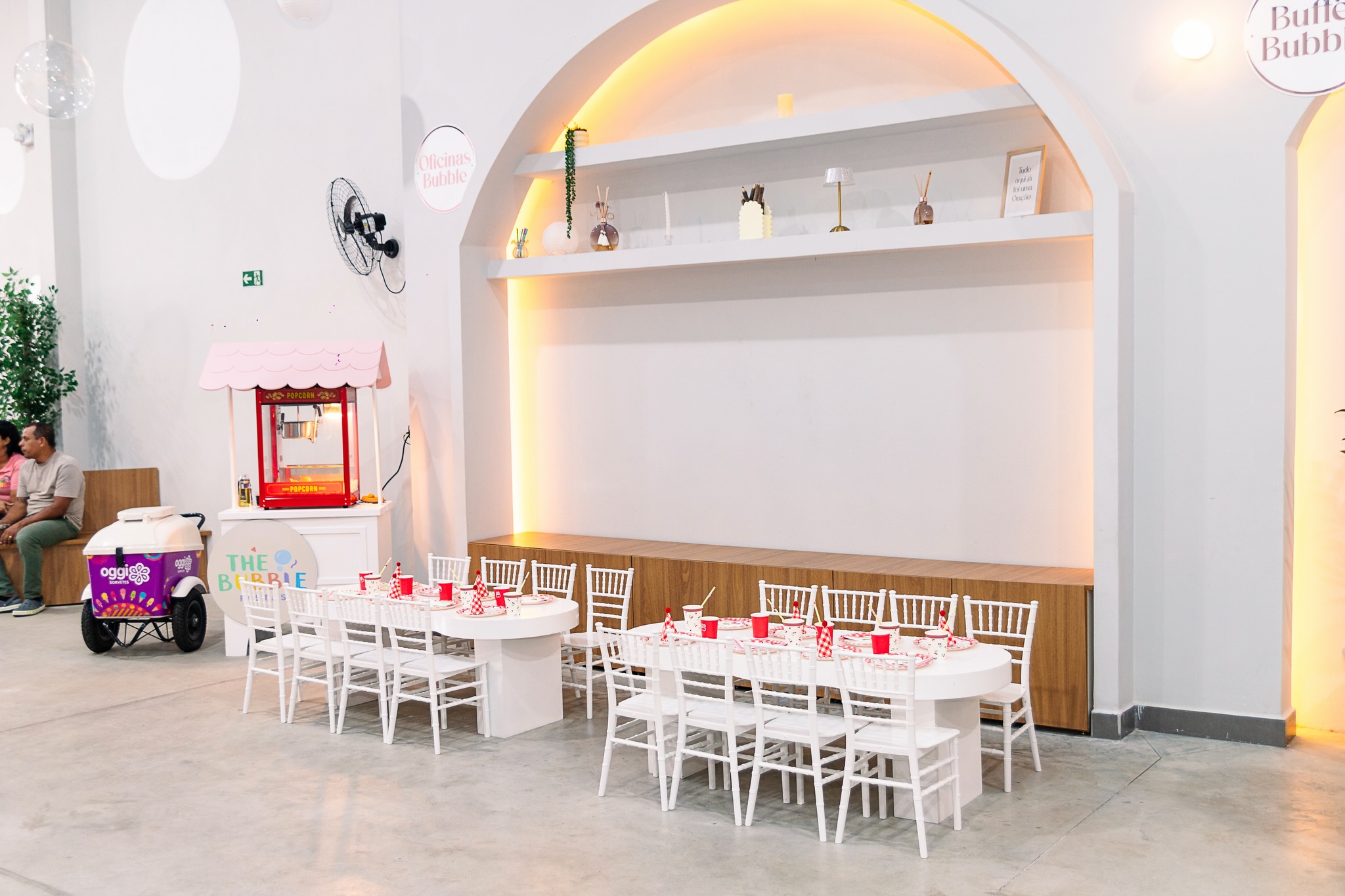 Lounge interno com arcos, nichos iluminados e mesinhas das crianças
