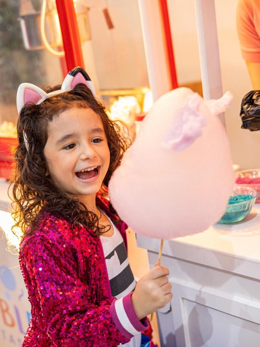 Criança sorrindo com algodão-doce na festa